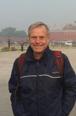 A smiling man with grey hair and a blue jacket. 